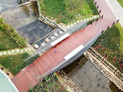 Wooden Landscape Bridge Spanning Stream With Green Vegetation And Paved Walkway 3d model