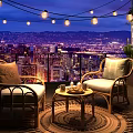 Outdoor Rattan Lounge Chairs With Side Table And String Lights Overlooking City Night View
