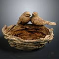 Two Bird Sculptures Perched On Woven Bird Nest Against Dark Background