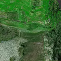 Aerial View Of Steep Rocky Terrain With Lush Green Vegetation And Path Near Water