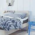 Double Bed With Wooden Headboard Gray Camouflage Quilt Striped Pillows And Blue Side Table