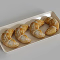 Four Fresh Croissants on a White Rectangular Plate Dusted with Powdered Sugar