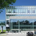 Modern Office Building With Glass Facade Stone Base And Tree Near Entrance With Cars