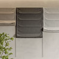 Fabric Curtains in Different Gray Tones Displayed on Beige Wall with Green Plant Accent