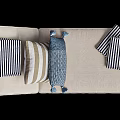 Wicker Lounge Chair with Beige Cushion Striped Pillows and Blue Throw Blanket
