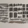 Assorted Metal Hardware Parts Including Bolts Hinges And Plates On White Surface