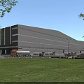 Modern Industrial Factory Building with Large Windows Trucks in Front Parking Area and Green Lawn
