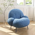 Blue Plush Rounded Lounge Chair With Black Metal Legs In Bright Room With Green Plant