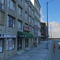 Vibrant Commercial Street With Multi Story Buildings Shop Signs Street Lamps And Traffic Cones