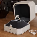 Elegant Diamond Ring Inside Open Jewelry Box With Pearl Detail And Small Ring On Wooden Table