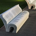 Outdoor Book Shaped Bench with Text Design on Paved Ground near Green Grass