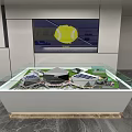 Sand Table Model In Glass Covered Display Case With Building Structures And Yellow Logo Screen
