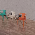 Three Colorful Plastic Leisure Chairs With Backrest And Armrests Against Gray Wall On Wooden Floor
