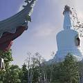 White Pagoda With Traditional Architectural Elements Surrounded by Green Trees Under Blue Sky