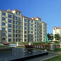 Modern Multi Story Residential Building With Red Roof White Exterior And Landscaped Courtyard