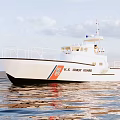 U.S. Coast Guard White Yacht Sailing On Calm Sea With Water Reflection Under Cloudy Sky