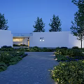 Modern Public Restroom With White Architecture Nighttime Lighting And Surrounding Green Plants