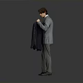 Man In Gray Suit With Red Tie Holding Dark Blue Suit Jacket Against Gray Background