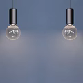 Four Modern Pendant Lights With Black Fixtures And Clear Glass Bulbs On Blue Wall