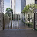 Modern Metal Entrance Gate With Stone Walls Trees And High Rise Buildings