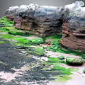 Coastal Rocky Landscape With Green Moss Covered Reddish Brown Cliffs And Sandy Puddles