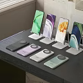 Various Smartphones Displayed On Stands With Colorful Wireless Chargers On Table