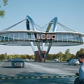 Modern Entrance Gate with Arch Structure Glass Panels Top LOGO Surrounded by Vehicles and Greenery