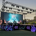 Outdoor Evening Stage With Metal Truss Lighting LED Screen Band Neon Decorations And Grass Background
