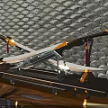 Crossed Swords with Golden Decorations on Black Geometric Wall Illuminated by Lights and Wooden Base