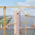 Massive Cable Stayed Bridge Under Construction With Tower Crane Spanning The Wide Calm River