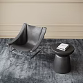 Gray Leather Lounge Chair With Round Side Table And Magazine On Gray Rug