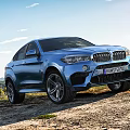 Blue BMW SUV Parked On Outdoor Dirt Road With Blue Sky White Clouds And Landscape