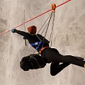 Man Rock Climbing On Wall With Safety Rope And Protective Gear