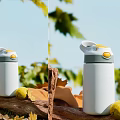 Stylish White Insulated Cup with Yellow Accent Lid Among Green Leaves and Lemon