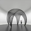 Black Arched Net Like Art Installation In White Gallery With Person Standing Beneath