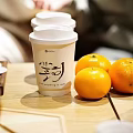 Paper Cup With White Lid Chinese Characters And Fresh Oranges On Table