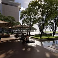 Modern Plaza Landscape with Glass Building Trees Geometric Pavement Umbrella Seating and Pedestrians