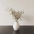 White Vase With White And Yellow Flowers On Dark Tabletop Light Colored Wall Background