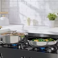 Stainless Steel Cooking Pans On Gas Stove With Blue Flames And Fresh Vegetables