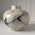 Cream Ceramic Vase With Navy Blue Crackle Pattern Against Wooden Plank Wall