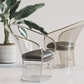 Transparent Leisure Chair With Gold Frame And Black Cushion Near Green Plant