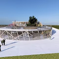 Modern Circular Building with Glass and Wooden Structure on Lawn by Blue Sky and Sea