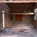 Abandoned Building Interior With Exposed Wooden Ceiling Damaged Walls Broken Windows And Floor Drainage Grate