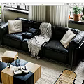 Black Leather Multi Person Sofa With Pillows And Knitted Blanket In Bright Living Room