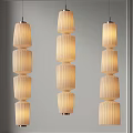 Three Modern Layered Pendant Lights With Textured Cylindrical Shades And Warm Glowing Light