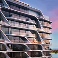 Modern Curved High Rise Apartment Building With Glass Facade Balconies And Ocean View Sunset Sky