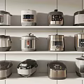 Neatly Arranged Kitchen Appliances Including Rice Cookers And Pressure Cookers On White Shelves