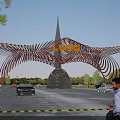 Modern Wing Shaped Metal Entrance Gate With Top LOGO Surrounded By Cars And Pedestrians