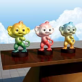 Three Colorful Monkey Sculptures On Wooden Table With Blue Sky White Clouds