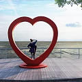 Red Heart shaped Landscape Sculpture On Seaside Wooden Platform With Person And Ocean View